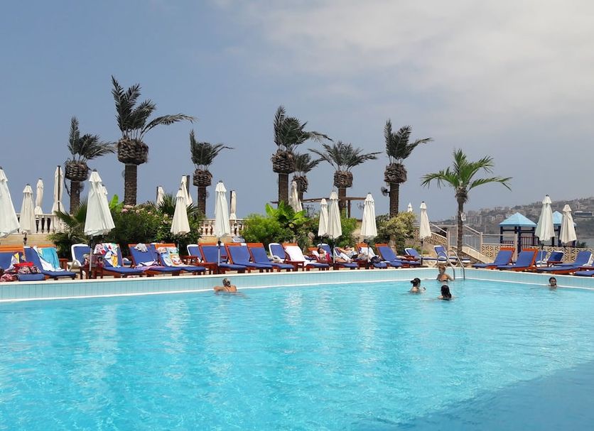 Lamedina Hotel & Resort in Jounieh: outdoor pool with loungers, umbrellas, palm trees, and sea view