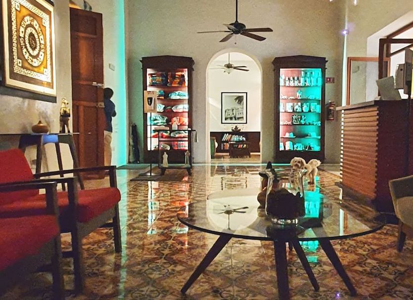 Merida Santiago Hotel Boutique in Mérida lobby with glass coffee table, patterned tile floor, and lit display cabinets.
