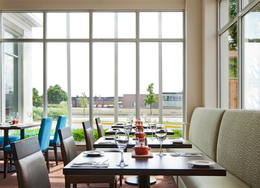 Hilton Garden Inn Montreal Airport dining area with large windows and tables overlooking greenery in Montreal