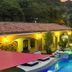 Las Brisas Resort and Villas in Jacó with pool, palm trees, and lit outdoor seating area