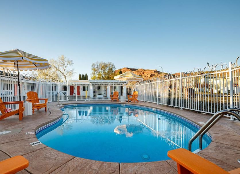 Quail Park Lodge in Kanab: outdoor pool with orange lounge chairs, umbrella, and mountain backdrop
