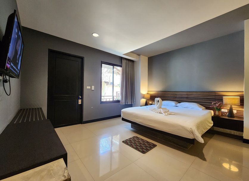 Pattaya Garden Resort in Pattaya guest room with king bed, wall-mounted TV, and window light