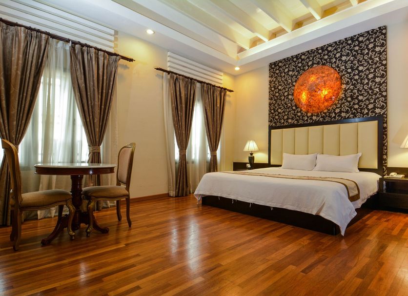Jonker Boutique Hotel in Malacca guest room with king bed, wooden floor, and seating by tall windows
