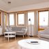 Guesthouse Brekka in Husavik living room with large windows, sofa, armchairs, and coffee tables