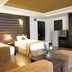 The Heritage Sathorn Suite Hotel Bangkok guest room with twin beds, sofa, and dark wood wardrobe