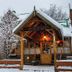 Hostal de la Laguna in Ushuaia, snowy wooden lodge exterior with lit entrance and winter trees