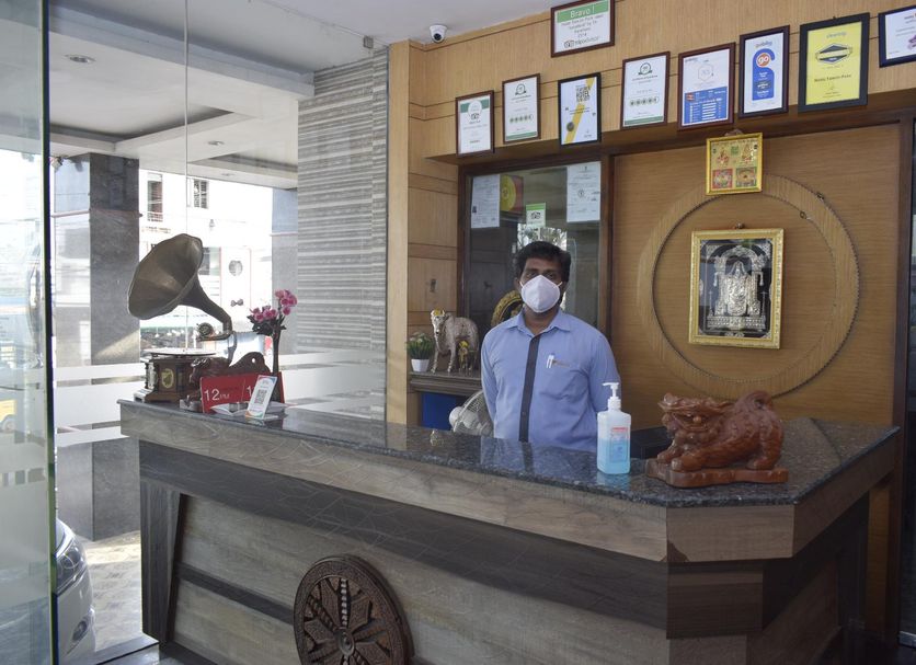 Hotel Tamizh Park lobby reception desk in Pondicherry with staff member and awards display