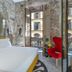 Hotel Calimala Florence room with stone walls, red chair and balcony view in Florence