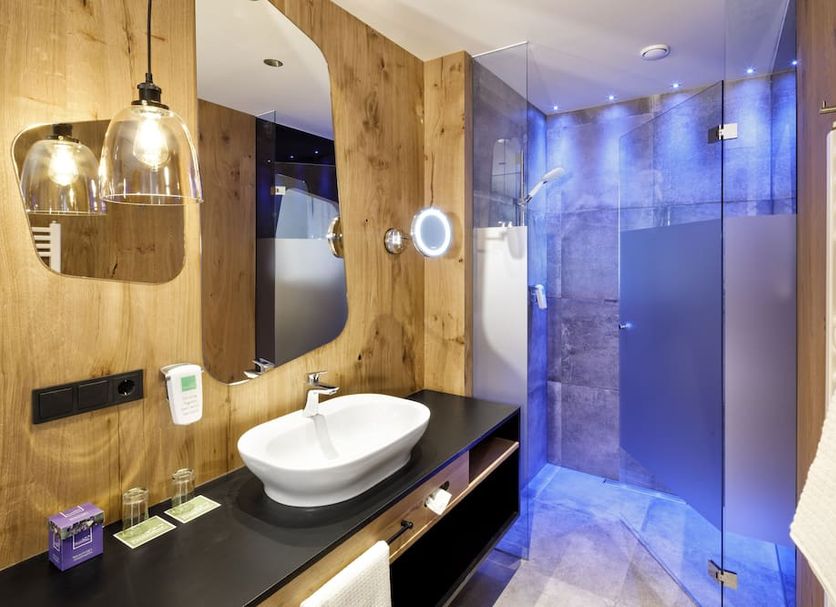 Hotel Penzinghof bathroom in Oberndorf in Tirol with vessel sink, wood vanity and glass shower