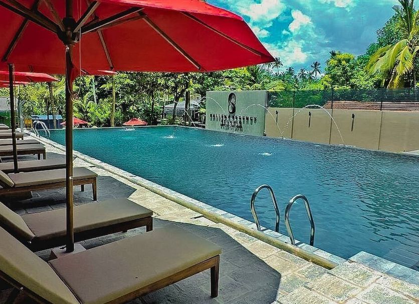 Ballena Regency in Mirissa: outdoor infinity pool with loungers, red umbrellas, and tropical greenery