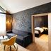 Hotel Zugbrücke Grenzau room with sofa, chair, table and bedroom doorway in Hohr Grenzhausen