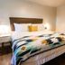 Stonewall Motor Lodge guest room with king bed, patterned blanket, nightstands and dresser in Stonewall