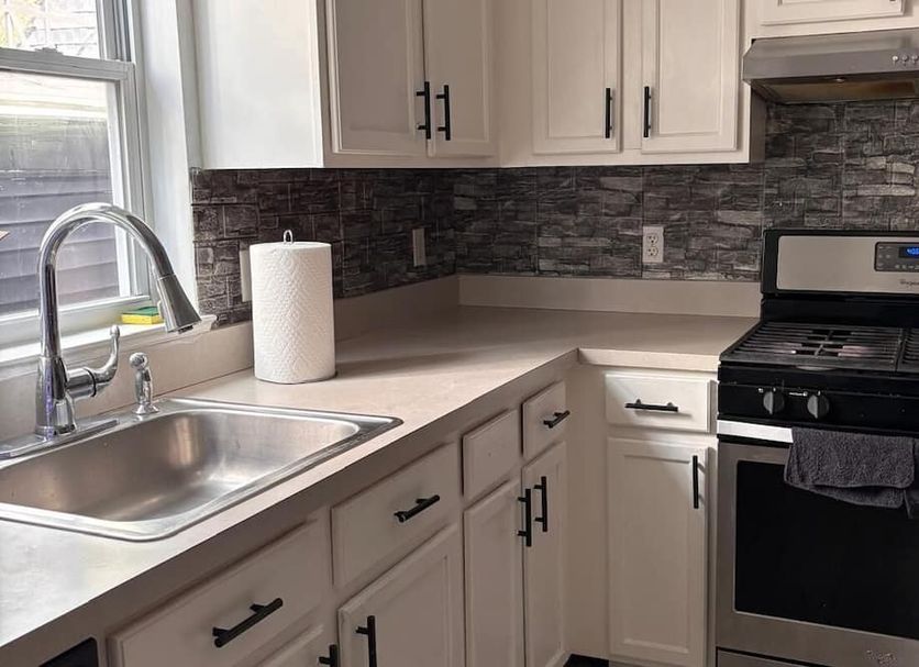 Nwk 457 Room 111-A in Newark kitchen with sink, stove, beige cabinets, and stone tile backsplash