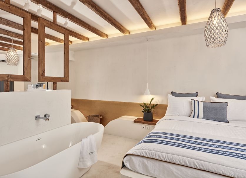 Parian Boutique Hotel in Parikia, elegant guest room with white bed, freestanding tub and wood beams