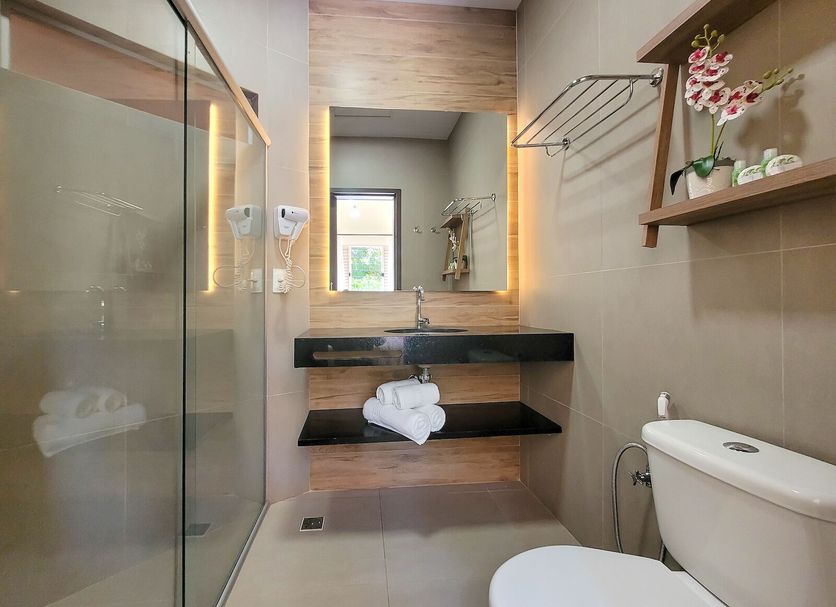 Hotel Pousada Aguas De Bonito bathroom with glass shower, vanity mirror, and toilet in Bonito