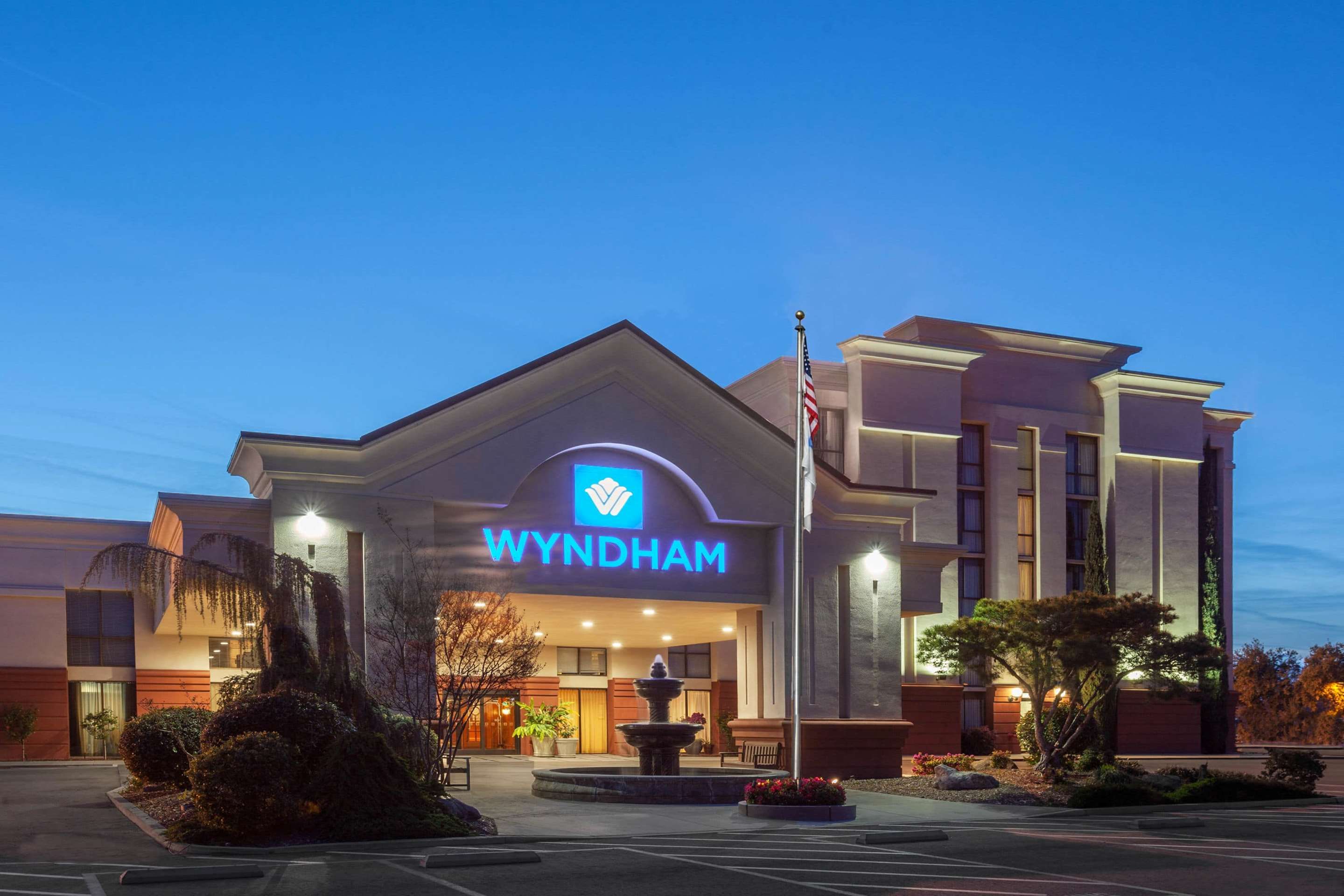 Wyndham Visalia exterior at dusk with lit entrance and fountain