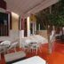 Hotel Santa Maria in Praia courtyard patio with white tables, chairs and a tree on orange flooring