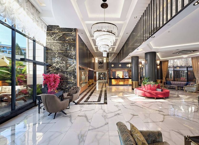 Grand Uysal Apart Hotel in Alanya lobby with marble floors, chandeliers, and red seating area