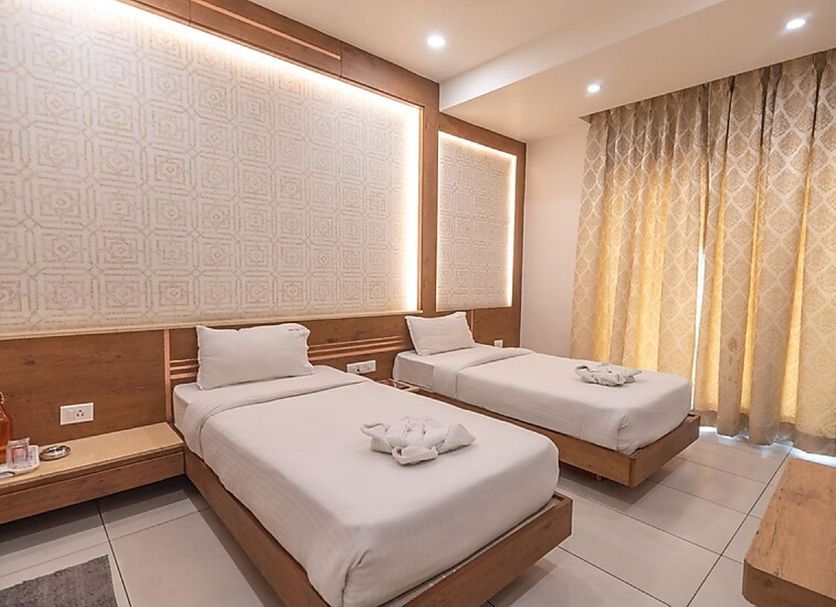 Hotel G Shy Bhopal twin room with two single beds, bedside table, and floor-length curtains