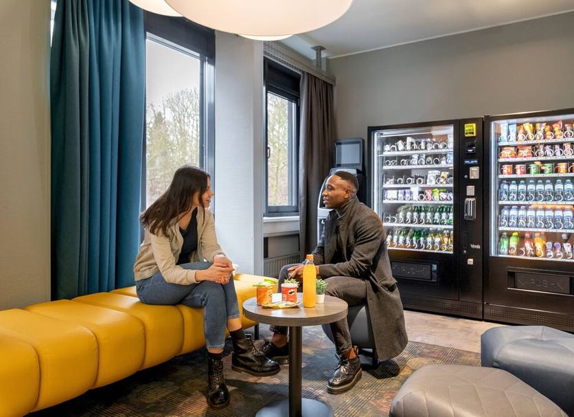 A&O Hamburg Hammer Kirche lounge with yellow bench seating and vending machines in Hamburg
