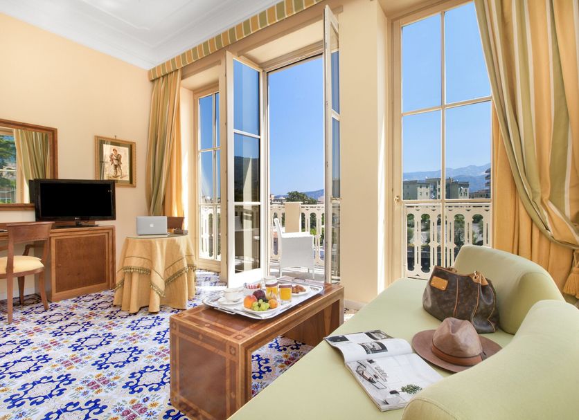 Hotel Antiche Mura in Sorrento suite with balcony doors, sea view, and sitting area
