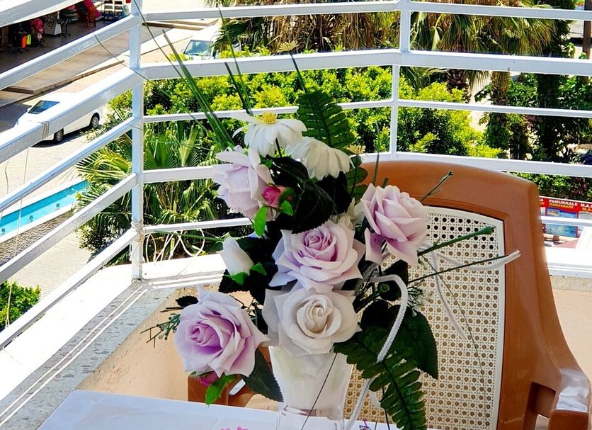 Palmen Apart Hotel in Alanya with balcony sea view, white railing, and table with flowers