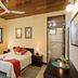 Hotel Jaguar Inn Tikal room with double bed, wood ceiling, windows, and adjoining tiled bathroom