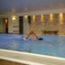 Flairhotel am Wörthersee indoor pool with a swimmer and stone wall in Velden am Wörthersee