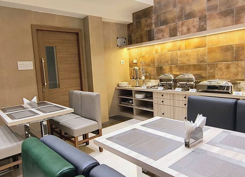 Zaith Residency Chennai breakfast area with tables, chairs, and buffet counter