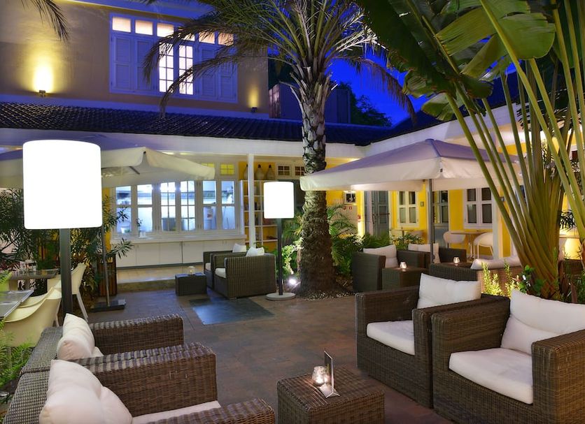 Boutique Hotel 't Klooster in Willemstad courtyard seating under palm trees with lit evening ambiance