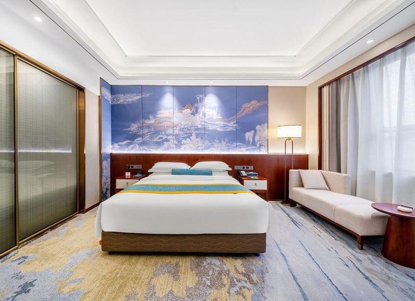 Anhui Construction New Era Hotel Bengbu guest room with king bed, sofa, and large window