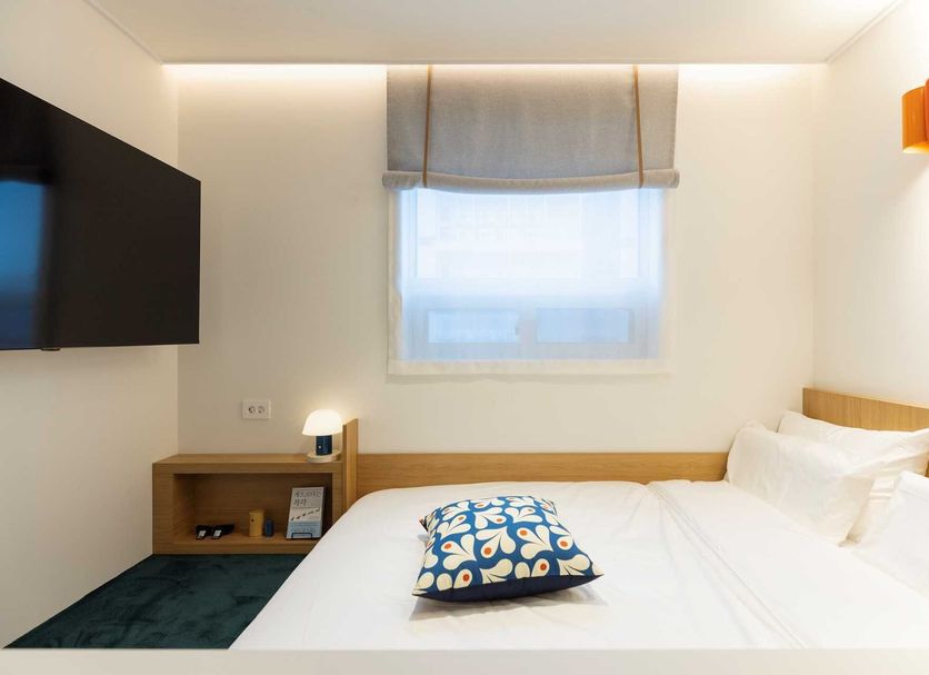 Nube Hotel & Spa Seoul Jongno guest room with bed, window, wall-mounted TV and bedside lamp in Seoul