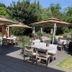 Outdoor terrace dining at Logis Hotel Le Petit Casset in La Boisse with tables, umbrellas and greenery
