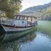 Hotel Riverside boat on a calm river in Dalyan, Mugla, beside forested cliffs