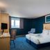 Travelodge Amesbury Stonehenge guest room with twin beds, blue carpet, desk and window view in Salisbury