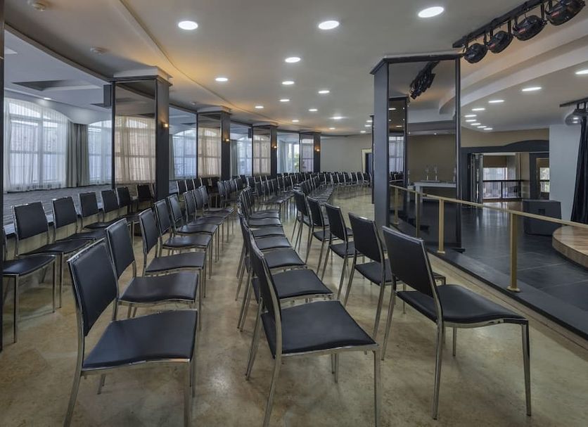 Hotel Lake House Kinneret in Tiberias event hall with rows of black chairs and a stage