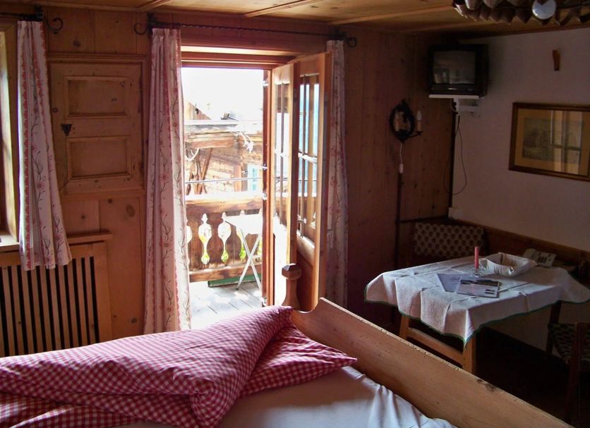 Gästehaus Bichl in Umhausen: cozy room with bed, table, and open balcony door to mountain view