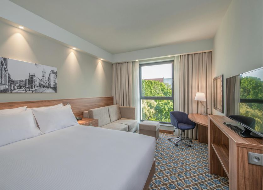 Hampton by Hilton Oswiecim room with king bed, sofa, desk, TV and window view in Oświęcim
