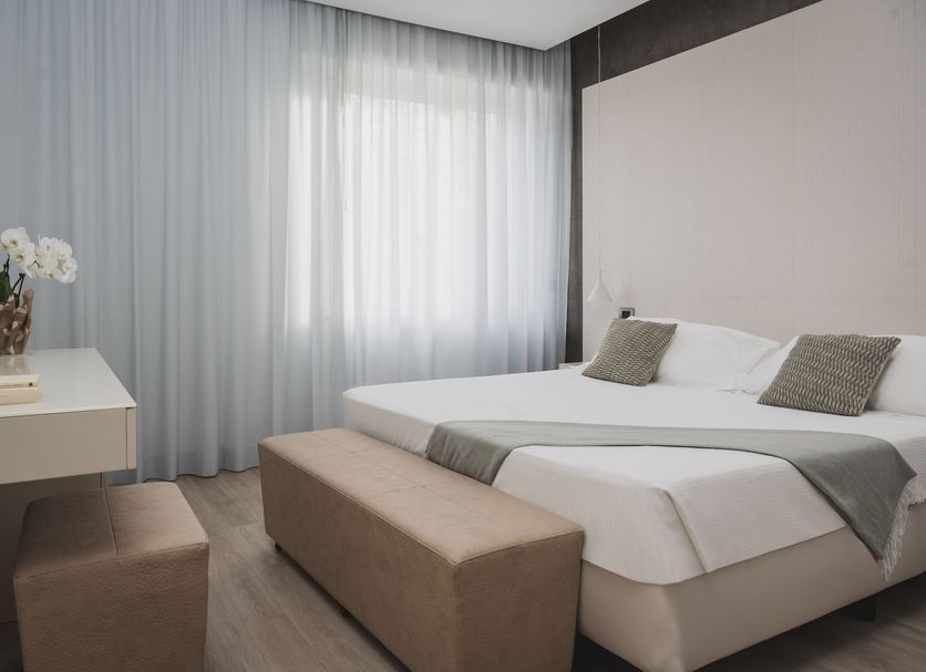 The Regent Boutique Hotel & Spa in San Marino guest room with bed, desk, bench and sheer curtains