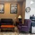 Hotel Piney Woods Huntsville lobby seating area with purple chairs, sofa, coffee table and wall art