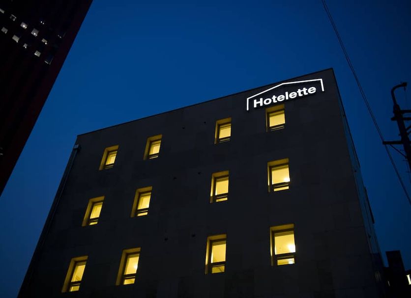 Hotelette Seoul Station in Seoul, exterior at night with lit windows against a blue sky.