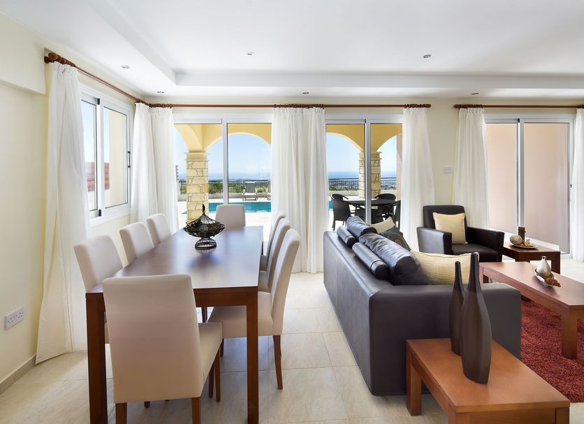 Club St. George, Paphos: bright suite with dining area, sofa, and balcony doors overlooking the sea