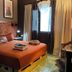 Coqui del Mar Guesthouse in San Juan guest room with double bed, pallet base, window curtains and framed wall art.