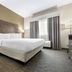 Best Western Brockport Inn & Suites guest room with king bed, window curtains, and bedside lamps in Brockport.