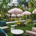 Hampton by Hilton Grand Cayman Seven Mile Beach courtyard with striped umbrellas, palm trees and outdoor seating in George Town