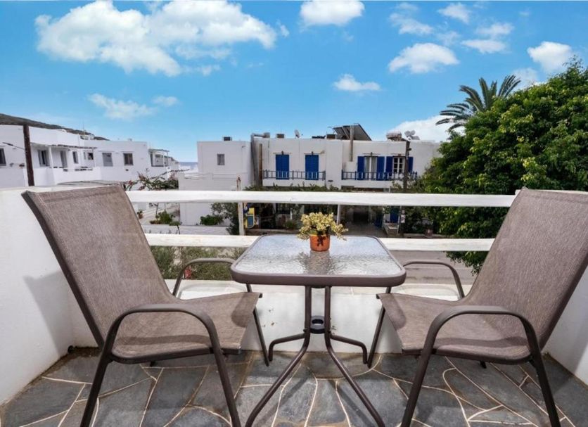 Cyclades Beach Apartments, Platis Gialos: balcony with two chairs, table, and view of white buildings and palm trees