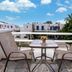 Cyclades Beach Apartments, Platis Gialos: balcony with two chairs, table, and view of white buildings and palm trees