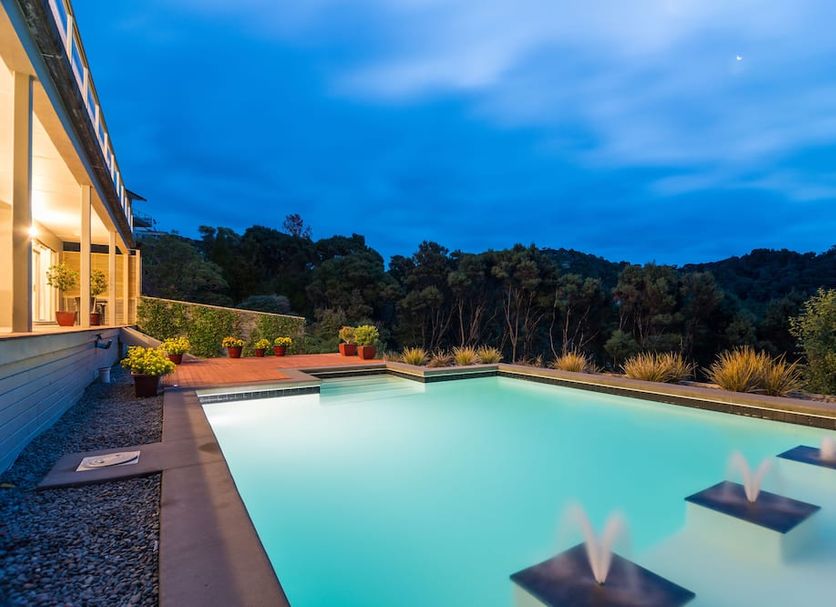 Decks of Paihia in Paihia with an outdoor pool and deck overlooking trees at dusk