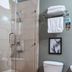 Le Plaza Hotel in Port Au Prince bathroom with glass shower, toilet, towel shelf, and framed wall art