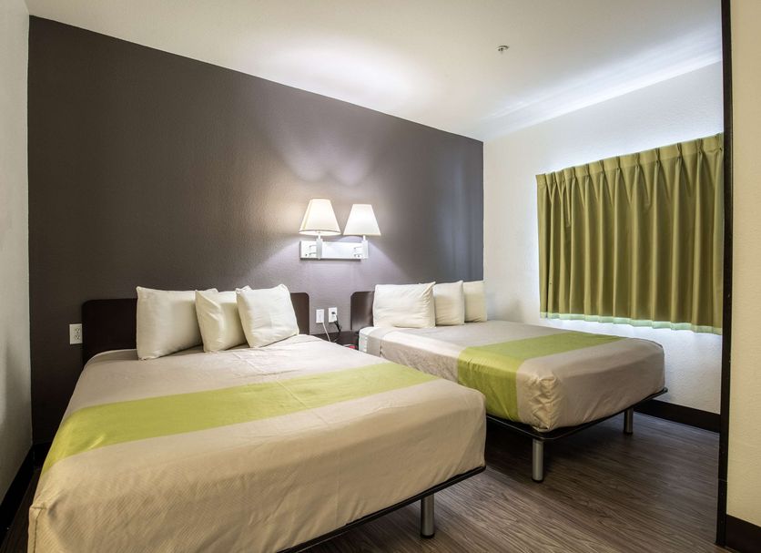 Studio 6 Bay City, TX guest room with two beds and a window with green curtains